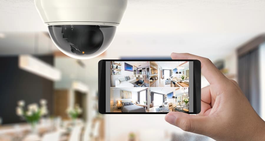 Homeowner holding smartphone with video feed from security cameras in San Antonio